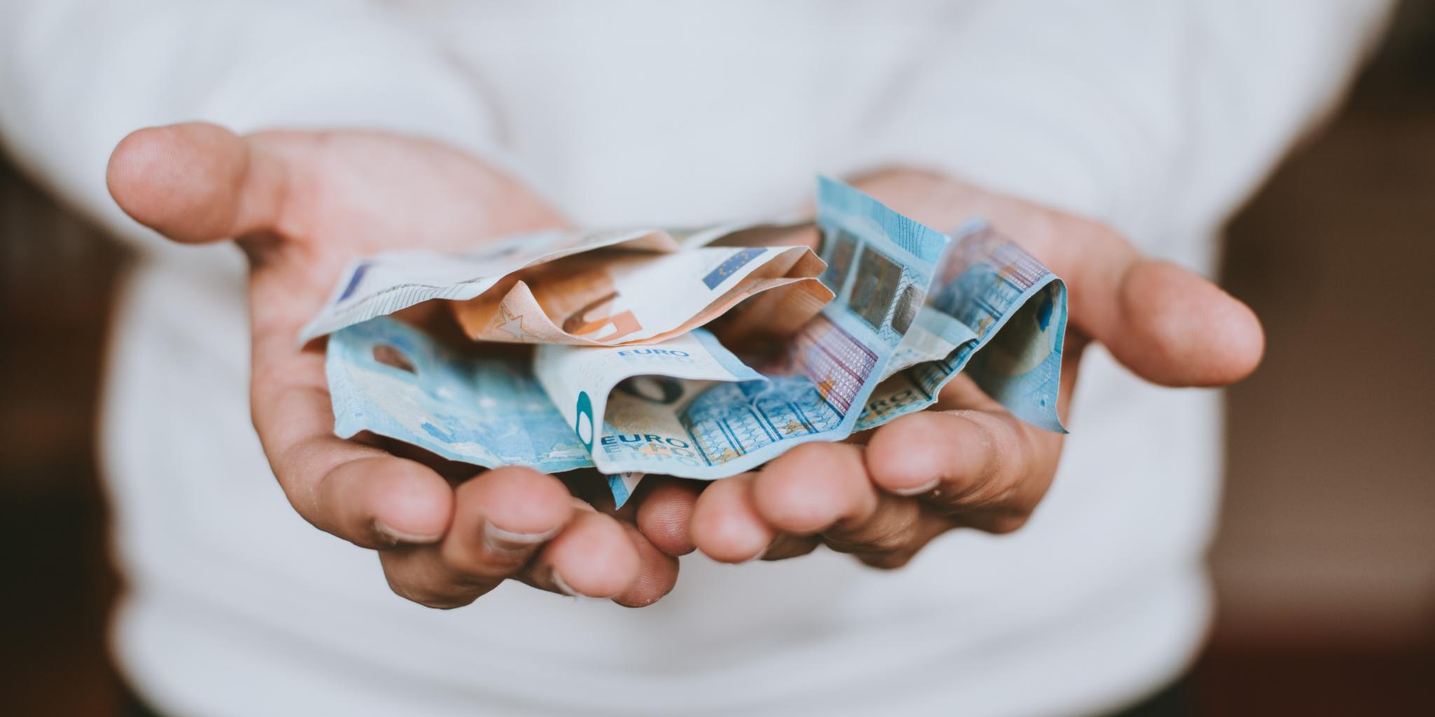 Zwei Hände sind zu einer offenen Schale gelegt mit Geldscheinen darauf (c) Unsplash/Christian Dubovan Zwei Hände sind zu einer offenen Schale gelegt mit Geldscheinen darauf